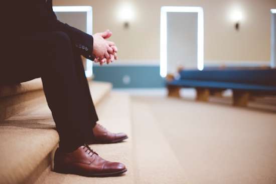 A man in a suit sits in the sanctuary, awaiting the church service.