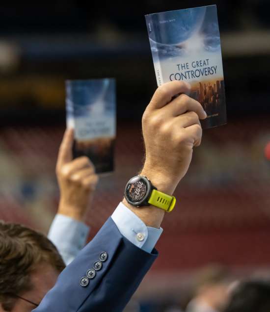 People in a crowd holding up copies of The Great Controversy.