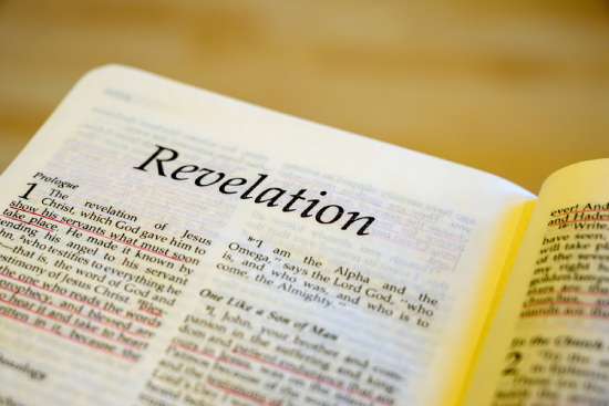 Close-up of the first page of Revelation, focusing on the title with the verses blurring