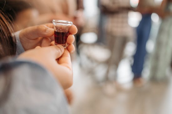 A person holds a communion cup while everyone waits for the cue to drink.