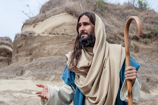 Jesus holding a shepherd's staff in one hand and reaching out in kindness with the other hand