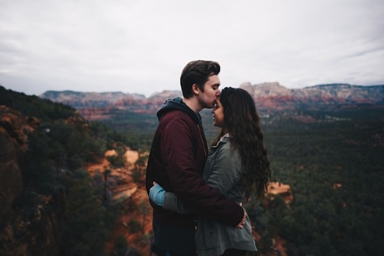 A man and woman embracing on top of a mountain