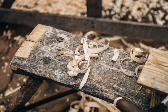 A piece of rough lumber with wood shavings on top, representing Jesus' trade as a carpenter