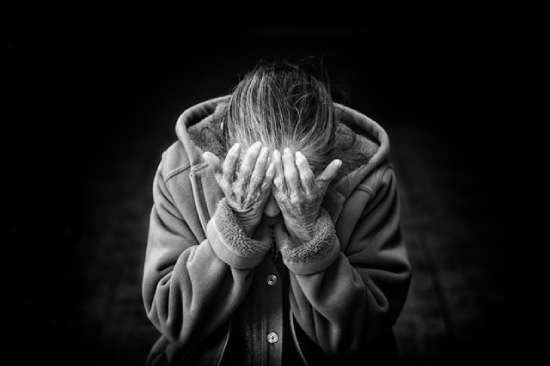 A woman leans forward with her hands covering her face. This is a common picture of when we think about grief.