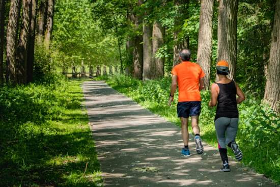 A man and woman run together on a trail in the forest, illustrating how exercise can help heal.