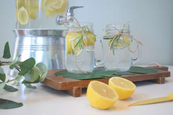 Two pitchers with lemon water, and a lemon cut in half on the table.