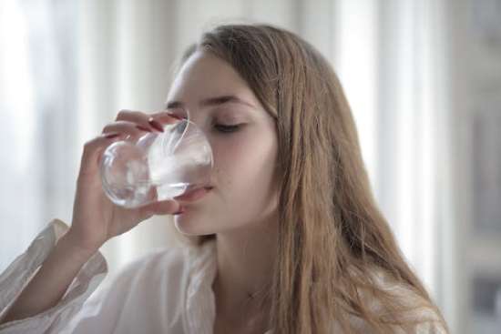 Young woman drinking water from a glass.