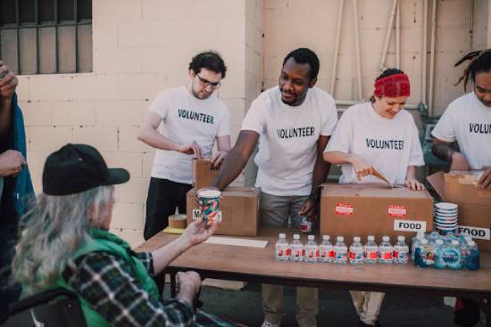 A group of volunteers hands out food and water, showing an example of mission projects.