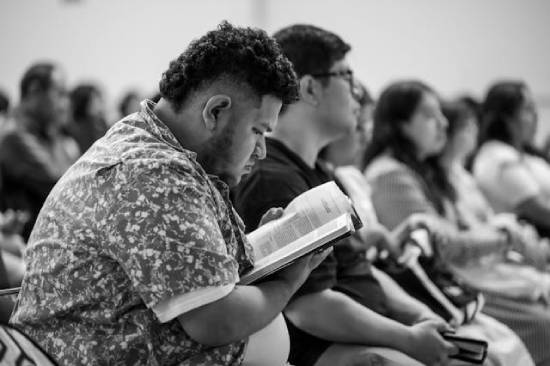 A man looks at his Bible during a sermon, highlighting how Sabbath school is a time to study God's Word.