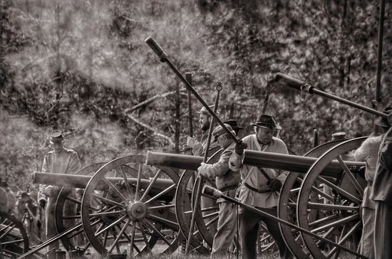 A black and white photo of soldiers manning cannons.