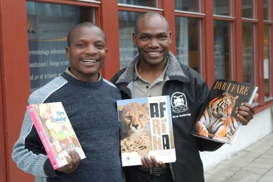 Two Adventist colporteurs holding up books they are selling