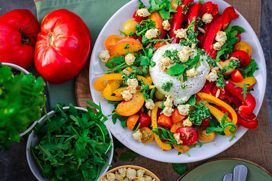 A plate of colorful peppers, tomatoes, and greens that could go on an Adventist meal of haystacks