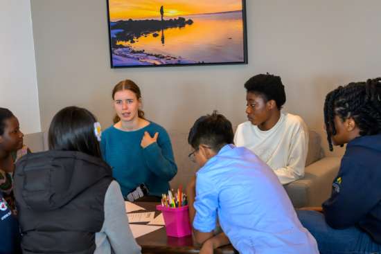 A group of young people engaged in a group discussion, emphasizing how important small group gatherings are for creating community among church youths.