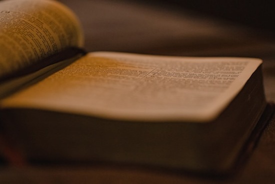  An open Bible in a dimly lit setting.