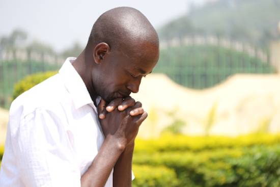 A black man glorifying God in prayer.