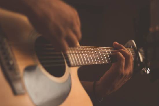 A man playing guitar. Guitars are one way we arrange tones, melodies, and rhythms.