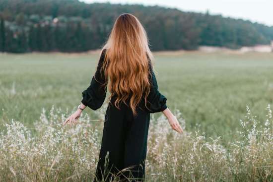 A woman dressed in black modestly walks through a field