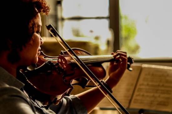 A woman plays a violin, an instrument known to make beautiful music.