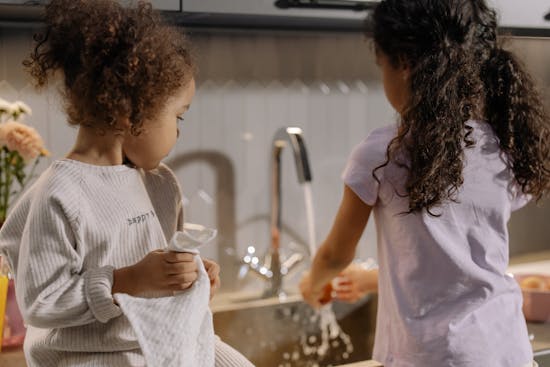 Two sisters washing and drying the dishes, which helps keeps the house clean and neat