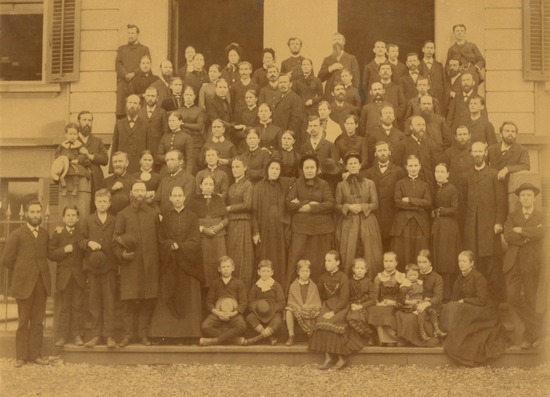 A sepia photo of Ellen G. White and many others at a conference in Basel, Switzerland. The image features several rows of people and includes a group of children sitting in the front.