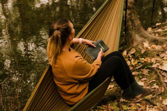 A woman sitting in a hammock, contemplating what she just read in her Bible