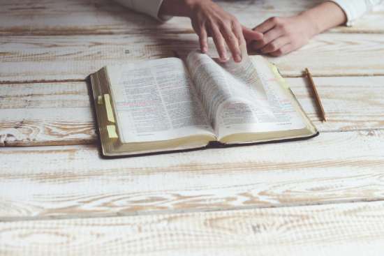 A person turning pages of a Bible as she studies Bible prophecy