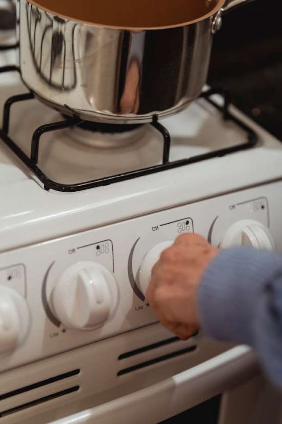 A close-up of a hand turning on one of the burners of a gas stove, illustrating the point that while heating food was a lot of work for the ancient Israelites, it's very easy now.