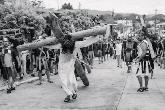 Jesus carrying a cross, surrounded by Roman soldiers