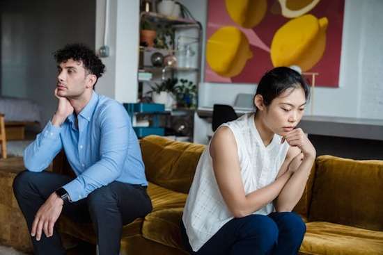 A couple looking frustrated and facing away from each other after a disagreement