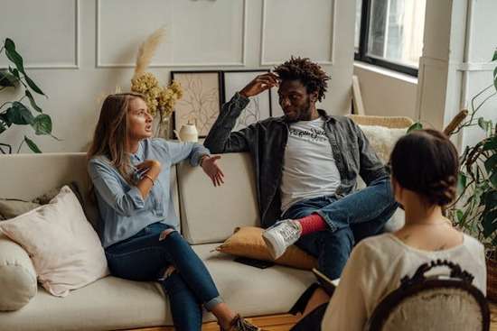 An interfaith couple sitting on a couch together during a counseling session