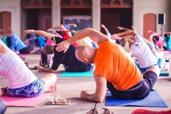 An exercise class stretches on their mats on the floor.