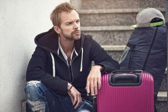 A man who's decided to divorce his wife sits by his suitcase on the stairs, preparing to move out of the house.