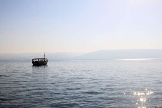 A boat floats away on the shimmering waters of the Sea of Galilee.