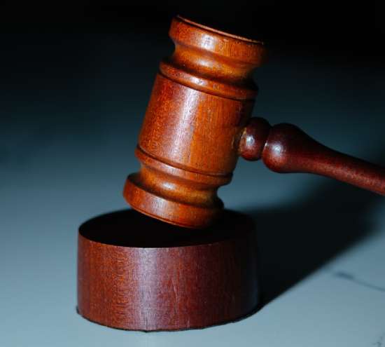 A wooden gavel hitting the top of a wooden block.