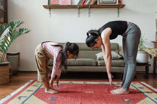 A woman and her daughter both stretching, reaching for their toes