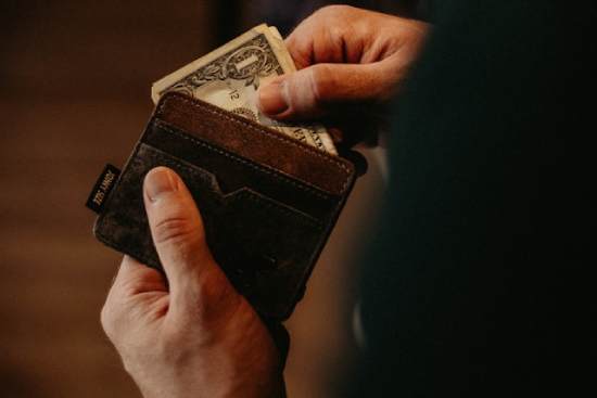 A man takes a dollar from his wallet.