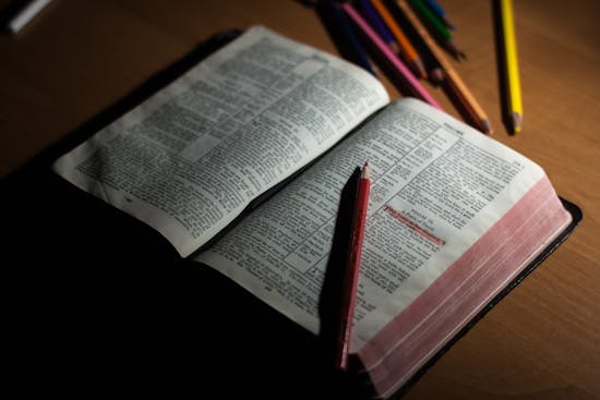 An open Bible surrounded by colored pencils for taking Bible study notes.